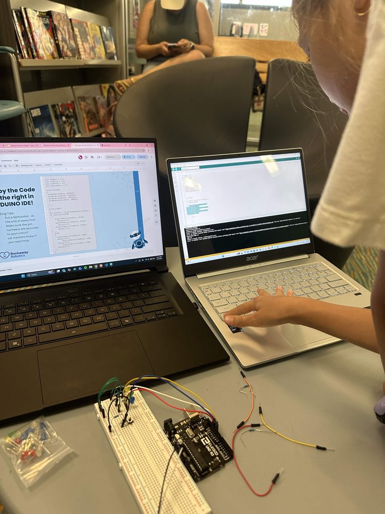 Student typing code on a laptop next to a breadboard circuit
