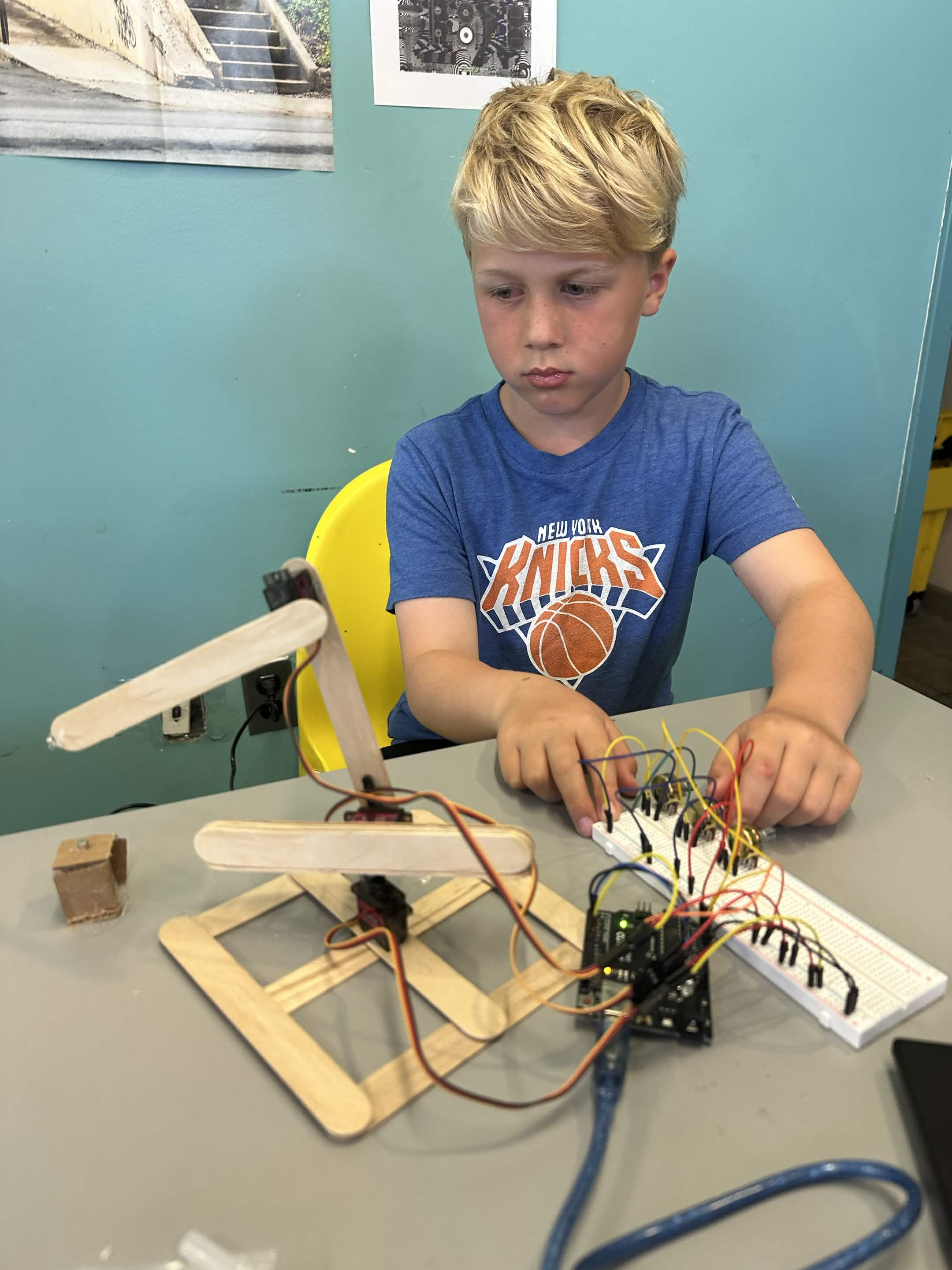 Student working on a servo-driven popsicle-stick robotic arm